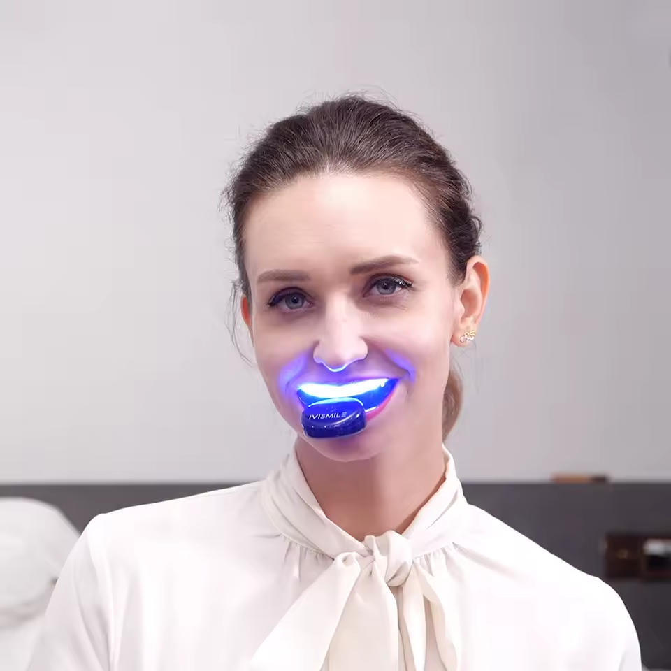 Woman using Genvita Pro teeth whitening device with blue light mouthpiece
